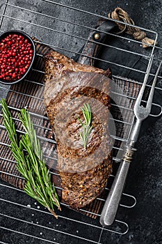 BBQ grilled tri tip beef steak on a grill. Black background. Top view