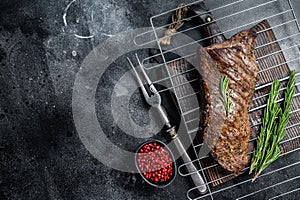 BBQ grilled tri tip beef steak on a grill. Black background. Top view. Copy space