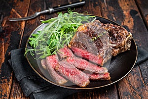 BBQ Grilled Wagyu New York beef meat steak or Striploin steak in a plate with salad. Wooden background. Top view