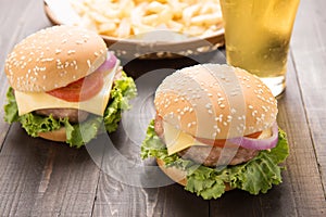 bbq hamburger with french fries and beer on the wooden background.