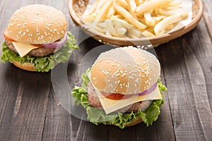 Bbq hamburger with french fries on the wooden background.