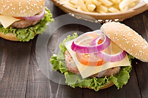 Bbq hamburger with french fries on the wooden background.