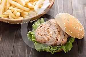 Bbq hamburger with french fries on the wooden background.