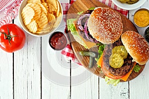 BBQ hamburgers with potato chips, overhead view table scene on white wood