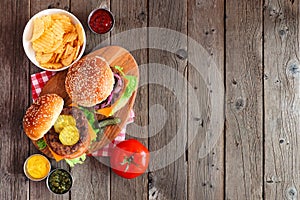 BBQ hamburgers on a serving board, above view on a dark wood background