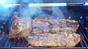 Bbq pork ribs cooking on flaming grill shot with selective focus