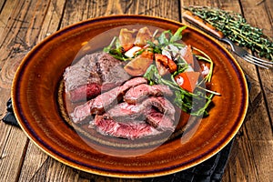 BBq roasted Oyster Top Blade or flat iron roast beef meat steak on a plate with salad. Wooden background. Top View