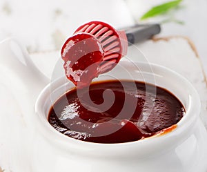 BBQ sauce in bowl with a brush.