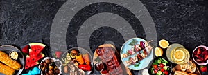 BBQ or summer picnic food border over a dark stone banner background, overhead view with copy space