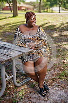 BBW big black beautiful model sitting on a park bench outdoors