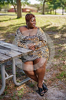 BBW big black beautiful model sitting on a park bench outdoors