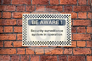 BE AWARE - security sign on brick wall background