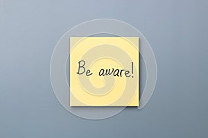 Be aware on yellow sticky note over a grey background. april fools day photo