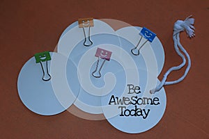 Be awesome today. Concept with positive note on white tag label papers and colorful smiling clips stationary