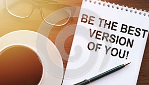 Be the best version of you, the text is written in a notebook with a cup of coffee and glasses on a wooden background