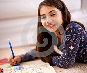 Be bold and color outside the lines. Portrait of a young girl coloring while lying on the floor.