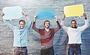 Be bold and speak your mind. Portrait of a group of young men holding speech bubbles against a brick wall.