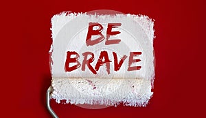 Be Brave. .One open can of paint with white brush on red background. Top view