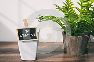 Be Creative text with cup of coffee and potted plant