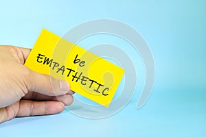 Be empathetic reminder concept. Hand holding a bright paper message note.