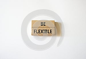 Be Flexible symbol. Wooden blocks with words Be Flexible. Businessman hand. Beautiful white background. Business and Be Flexible