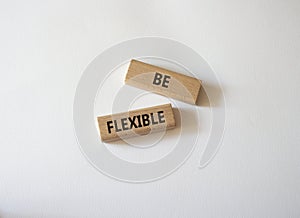 Be Flexible symbol. Wooden blocks with words Be Flexible. Businessman hand. Beautiful white background. Business and Be Flexible