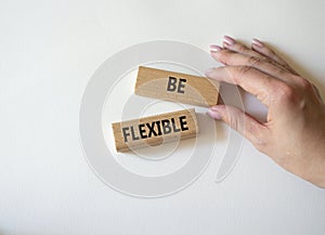 Be Flexible symbol. Wooden blocks with words Be Flexible. Businessman hand. Businessman hand. Beautiful white background. Business