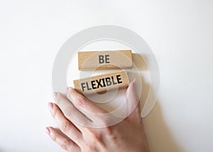 Be Flexible symbol. Wooden blocks with words Be Flexible. Businessman hand. Businessman hand. Beautiful white background. Business