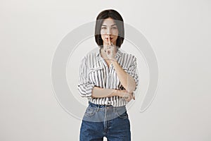 Be good and keep secret safe. Portrait of playful attractive young european woman in stylish striped blouse, smiling