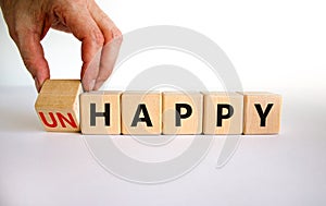 Be happy, do not unhappy symbol. Businessman turns the wooden cube and changes the word `unhappy` to `happy`. Beautiful white