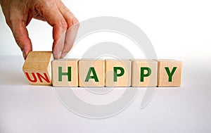 Be happy, do not unhappy symbol. Businessman turns the wooden cube and changes the word `unhappy` to `happy`. Beautiful white