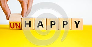 Be happy, do not unhappy symbol. Businessman turns the wooden cube and changes the word `unhappy` to `happy`. Beautiful yellow