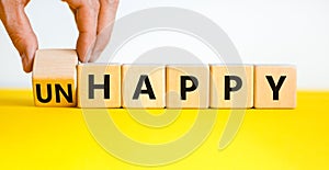 Be happy, do not unhappy symbol. Businessman turns the wooden cube and changes the word `unhappy` to `happy`. Beautiful yellow