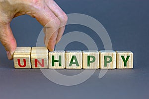 Be happy, do not unhappy symbol. Businessman turns wooden cubes and changes the word `unhappy` to `happy`. Beautiful grey