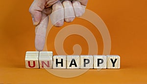 Be happy, do not unhappy symbol. Businessman turns wooden cubes and changes the word `unhappy` to `happy`. Beautiful orange