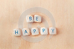 Be happy short phrase made with wooden letter blocks on a wooden background