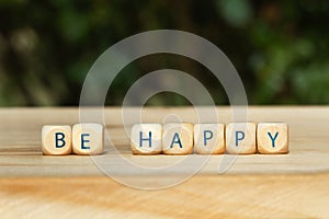 Be happy short phrase made with wooden letter blocks on a wooden table