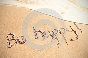 Be happy text written on sand