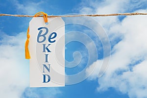 Be Kind message white gift tag over sky