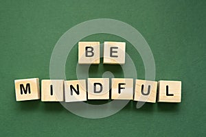 Be mindful word, quote written on a wooden green background. Meditation and welbeing concept