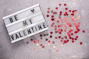 Be my Valentine with red heart shaped glitter on cement background