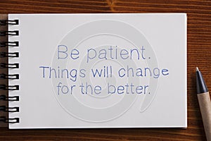 Be patient handwritten text on a notebook with pen