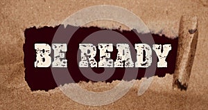 Be Ready words appearing behind torn brown paper. Business startup or virus prevention concept