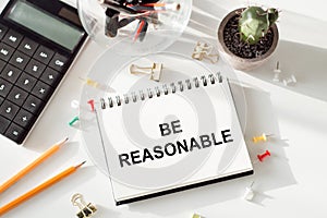 Be reasonable - text written on notebook on ofiice table