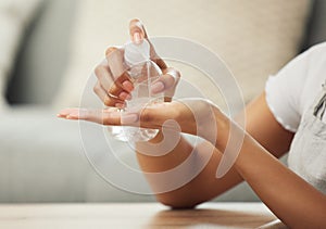 Be safe and sanitise. an unrecognizable woman sanitising her hands at home. photo