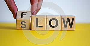 Be slow or in the flow. Male hand turns a cube and changes the word `slow` to `flow`. Beautiful yellow table, white background