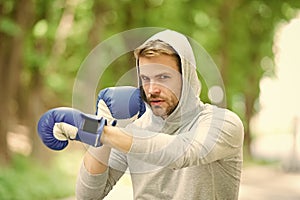 Be strong. man in boxing gloves punching. Sport and sportswear fashion. boxer man in hood. ready to fight. knockout and