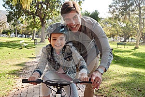 Be there for every memorable moment. an adorable little girl learning to ride a bicycle with her father in the park.