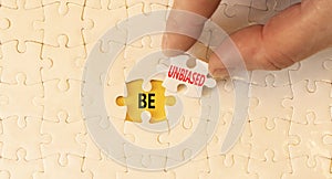 Be unbiased symbol. Concept words Be unbiased on white paper puzzles. Beautiful yellow table yellow background. Businessman hand.