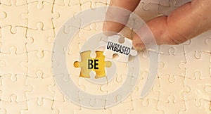 Be unbiased symbol. Concept words Be unbiased on white paper puzzles. Beautiful yellow table yellow background. Businessman hand.